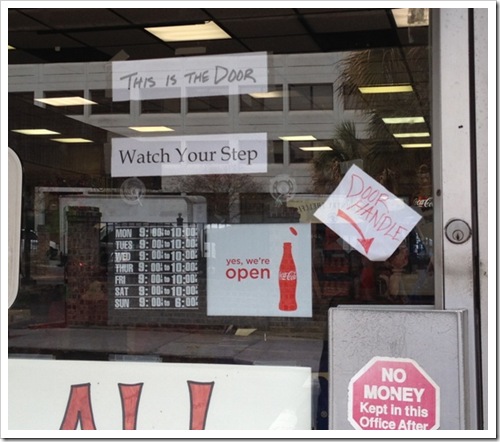 Shop window with sign pointing to door handle